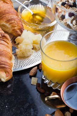 Kahvaltı çeşitli yoğurt, granola, kahve, meyve suyu, kruvasan, zeytin. Meze sabah yemekleri ile karıştırın. Koyu arka plan üzerinde sağlıklı, taze, lezzetli yemek