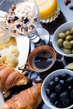 Kahvaltı çeşitli yoğurt, granola, kahve, meyve suyu, kruvasan, zeytin. Meze sabah yemekleri ile karıştırın. Koyu arka plan üzerinde sağlıklı, taze, lezzetli yemek