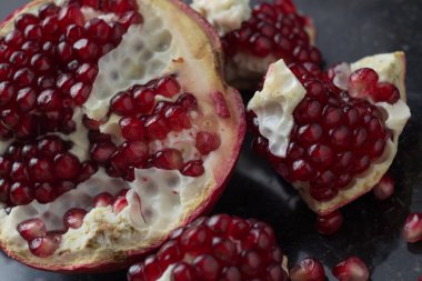 Karanlık mermer zemin üzerine kırmızı sulu nar. Sağlıklı, antioksidan, taze, gurme, lezzetli, organik meyve. Nar suyu için madde. Yakın çekim ve kopya alanı