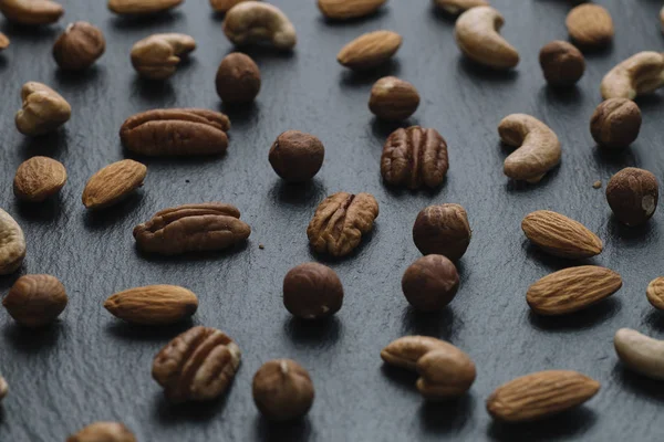 Karışık Kuruyemiş - badem, fındık ve kaju - karanlık arduvaz arka plan kopya alanı ile çeşitli. Üstten Görünüm. Tonda