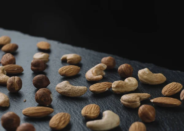 Mängd blandade nötter - mandel, hasselnötter och cashew - på mörk skiffer bakgrunden med kopia utrymme. Ovanifrån. Tonas — Stockfoto