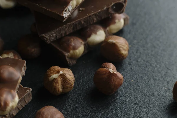 Schokoriegel und Nüsse auf dunklem Hintergrund mit Kopierraum. Schokoladenhintergrund. gemildert — Stockfoto