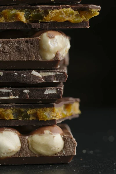 Çikolata parçaları ve fındık kopya alanı ile koyu arka plan üzerinde bar. Çikolata arka plan. Tonda