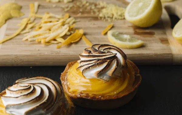 Lemon pie on the table with citrus fruits. Traditional french sweet pastry tart. Delicious, appetizing, homemade dessert with lemon cream. Copy space, closeup. Selective focus. Toned