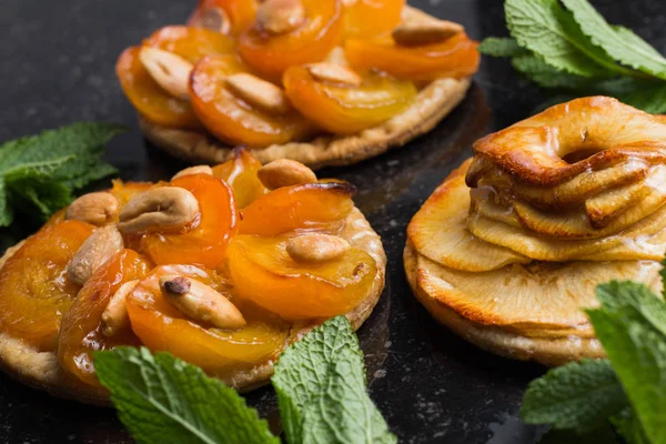 Kayısı ve elma tart. Karanlık mermer zemin üzerine meyve ile geleneksel Fransız pasta. Bir şekilde dekore edilmiş badem ve nane yaprakları. Kopyalama alanı closeup ile lezzetli tatlı