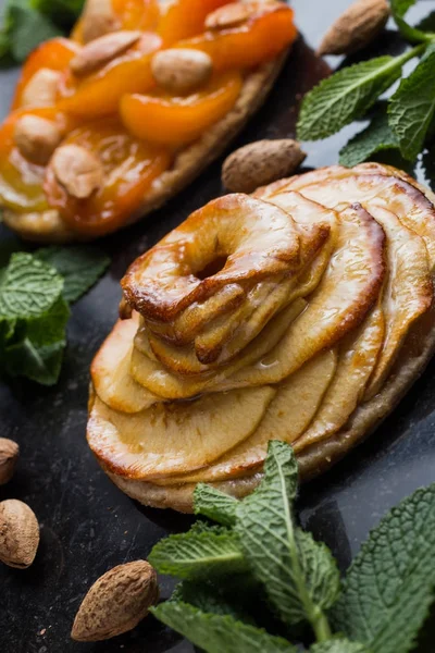 Kayısı ve elma tart. Karanlık mermer zemin üzerine meyve ile geleneksel Fransız pasta. Bir şekilde dekore edilmiş badem ve nane yaprakları. Kopyalama alanı closeup ile lezzetli tatlı