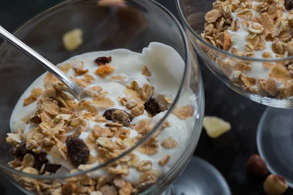 Granola con yogurt, noci e frutta in ciotola di vetro su fondo scuro. Delizioso dolce dolce sano per colazione. Cereali, muesli. Copia spazio, primo piano — Foto Stock