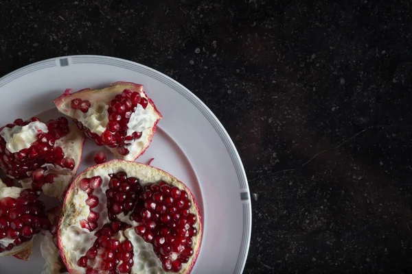 Red juicy pomegranate on dark marble background. Healthy, antioxidant, fresh, gourmet, delicious, organic fruit. Ingredient for grenadine. Close-up and copy space — Stock Photo, Image