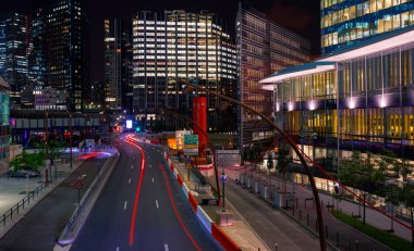 Paris iş içinde gökdelenler La Defense bölge. Avrupa gece cityscape dinamik sokak trafik, araba ışıklar ve modern binalar cam cephe ile. Ekonomi, Maliye, Ulaştırma kavramı. Tonda
