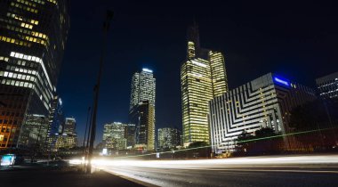 Paris iş içinde gökdelenler La Defense bölge. Avrupa gece cityscape dinamik sokak trafik, araba ışıklar ve modern binalar cam cephe ile. Ekonomi, Maliye, Ulaştırma kavramı. Tonda