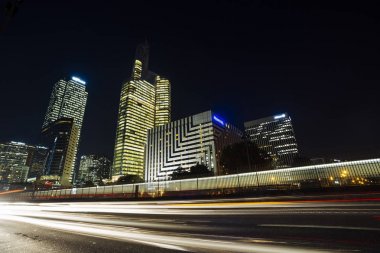 Paris iş içinde gökdelenler La Defense bölge. Avrupa gece cityscape dinamik sokak trafik, araba ışıklar ve modern binalar cam cephe ile. Ekonomi, Maliye, Ulaştırma kavramı. Tonda