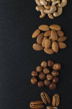 Karışık Kuruyemiş - badem, fındık ve kaju - karanlık arduvaz arka plan kopya alanı ile çeşitli. Üstten Görünüm. Tonda