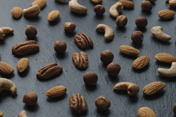 Karışık Kuruyemiş - badem, fındık ve kaju - karanlık arduvaz arka plan kopya alanı ile çeşitli. Üstten Görünüm. Tonda