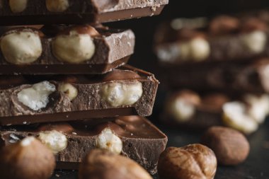 Çikolata parçaları ve fındık kopya alanı ile koyu arka plan üzerinde bar. Çikolata arka plan. Tonda