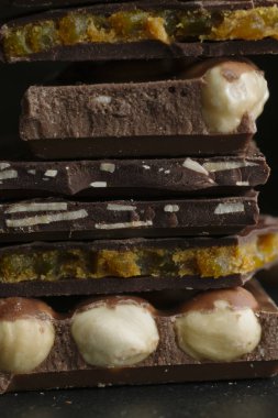 Çikolata parçaları ve fındık kopya alanı ile koyu arka plan üzerinde bar. Çikolata arka plan. Tonda