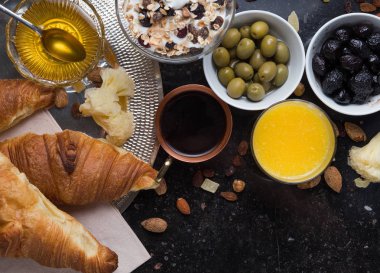 Kahvaltı çeşitli yoğurt, granola, kahve, meyve suyu, kruvasan, zeytin. Meze sabah yemekleri ile karıştırın. Koyu arka plan üzerinde sağlıklı, taze, lezzetli yemek