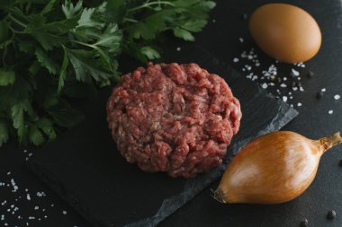 Çiğ biftek. Sığır eti çiğ et baharat, ot ve yumurta sarısı ile kıyılmış. Taze, baharatlı, lezzetli, gurme yemek ile kopya alanı, koyu arka plan üzerinde yakın çekim