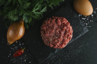 Çiğ biftek. Sığır eti çiğ et baharat, ot ve yumurta sarısı ile kıyılmış. Taze, baharatlı, lezzetli, gurme yemek ile kopya alanı, koyu arka plan üzerinde yakın çekim