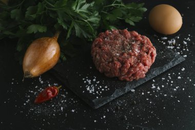 Çiğ biftek. Sığır eti çiğ et baharat, ot ve yumurta sarısı ile kıyılmış. Taze, baharatlı, lezzetli, gurme yemek ile kopya alanı, koyu arka plan üzerinde yakın çekim