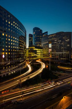 Paris iş içinde gökdelenler La Defense bölge. Avrupa gece cityscape dinamik sokak trafik, araba ışıklar ve modern binalar cam cephe ile. Ekonomi, Maliye, Ulaştırma kavramı. Tonda