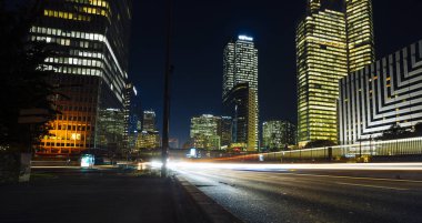 Paris iş içinde gökdelenler La Defense bölge. Avrupa gece cityscape dinamik sokak trafik, araba ışıklar ve modern binalar cam cephe ile. Ekonomi, Maliye, Ulaştırma kavramı. Tonda