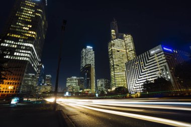 Paris iş içinde gökdelenler La Defense bölge. Avrupa gece cityscape dinamik sokak trafik, araba ışıklar ve modern binalar cam cephe ile. Ekonomi, Maliye, Ulaştırma kavramı. Tonda