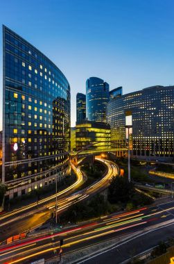 Paris iş içinde gökdelenler La Defense bölge. Avrupa gece cityscape dinamik sokak trafik, araba ışıklar ve modern binalar cam cephe ile. Ekonomi, Maliye, Ulaştırma kavramı. Tonda