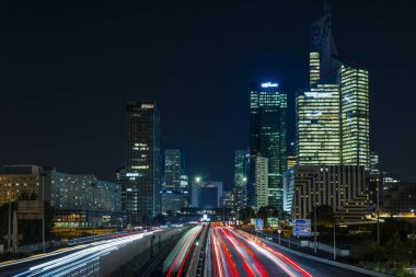 Paris iş içinde gökdelenler La Defense bölge. Avrupa gece cityscape dinamik sokak trafik, araba ışıklar ve modern binalar cam cephe ile. Ekonomi, Maliye, Ulaştırma kavramı. Tonda