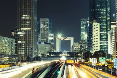 Paris iş içinde gökdelenler La Defense bölge. Avrupa gece cityscape dinamik sokak trafik, araba ışıklar ve modern binalar cam cephe ile. Ekonomi, Maliye, Ulaştırma kavramı. Tonda