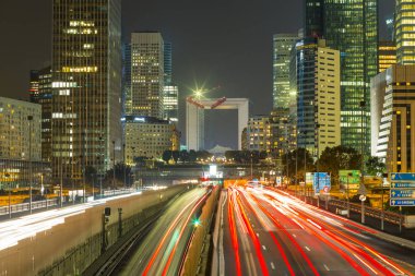 Paris iş içinde gökdelenler La Defense bölge. Avrupa gece cityscape dinamik sokak trafik, araba ışıklar ve modern binalar cam cephe ile. Ekonomi, Maliye, Ulaştırma kavramı. Tonda