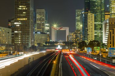 Paris iş içinde gökdelenler La Defense bölge. Avrupa gece cityscape dinamik sokak trafik, araba ışıklar ve modern binalar cam cephe ile. Ekonomi, Maliye, Ulaştırma kavramı. Tonda
