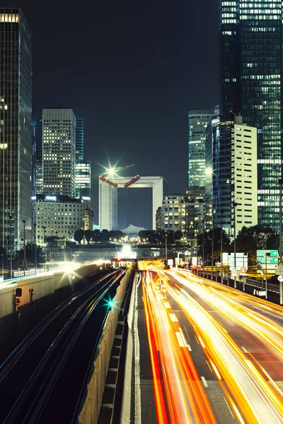 Paris iş içinde gökdelenler La Defense bölge. Avrupa gece cityscape dinamik sokak trafik, araba ışıklar ve modern binalar cam cephe ile. Ekonomi, Maliye, Ulaştırma kavramı. Tonda