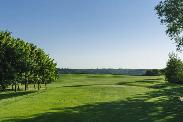 Vista general de un campo de golf verde en un día soleado brillante. Paisaje idílico de verano. Deporte, relax, recreación y ocio —  Fotos de Stock