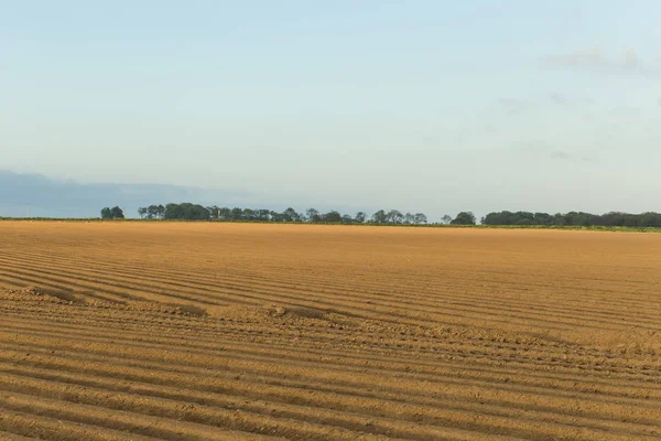 Gepflügte landwirtschaftliche Felder, die für den Anbau von Feldfrüchten in der Normandie vorbereitet wurden. Landschaft mit bewölktem Himmel, Ackerland im Frühling. umweltfreundliche Landwirtschaft und Konzept der industriellen Landwirtschaft — Stockfoto