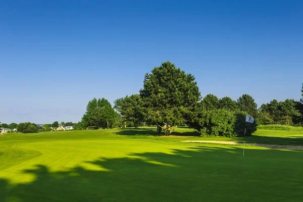 Generel udsigt over en grøn golfbane på en lys solskinsdag. Idyllisk sommerlandskab. Sport, slappe af, rekreation og fritid koncept - Stock-foto
