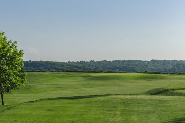 Yeşil bir golf sahası parlak güneşli bir günde bir genel bakış. Pastoral yaz manzara. Spor, sakin ol, rekreasyon ve eğlence kavramı
