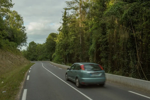 Αυτοκίνητα οδήγηση στην άσφαλτο περνώντας μέσα από το καταπράσινο δάσος στην περιοχή της Νορμανδία, Γαλλία. Καλοκαίρι φύση, εξοχικό τοπίο, μεταφορά και έννοια οδικό δίκτυο. — Φωτογραφία Αρχείου