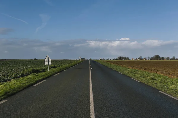 Asphalt road passing through the fields in the region of Normandy, France. Landscape in autumn sunny day. Toned — Stock Photo, Image