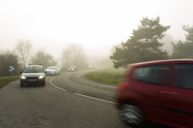 Ormanın içinden geçen arabalar ile eğri yol sisli asfalt. Normandy, Fransa bölgedeki düşük görünürlük ile hava durumu. Ülke manzara sisli gün. Tonda