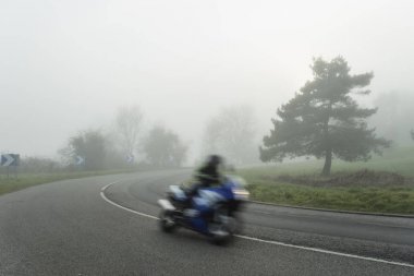 Ormanın içinden geçen Bisiklet ile eğri yol sisli asfalt. Normandy, Fransa bölgedeki düşük görünürlük ile hava durumu. Ülke manzara sisli gün. Tonda