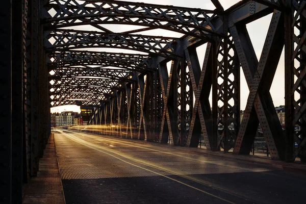 Asphalt road under the steel construction of a city bridge on a sunny day. Urban scene in the bridge tunnel. Long exposure. Toned — Stock Photo, Image