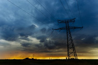 Yüksek gerilim enerji hatları ve enerji nakil direkleri gün batımında. Polonyalılar ve genel gider güç hatları siluetleri dusk içinde. Elektrik üretim ve dağıtım. Elektrik Sanayi ve doğa kavramı