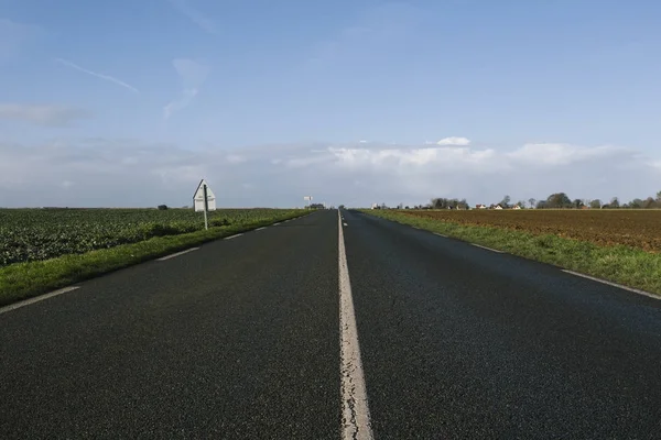 Асфальтовая дорога, проходящая через поля в регионе Нор, Франция. Пейзаж в осенний солнечный день. Toned — стоковое фото