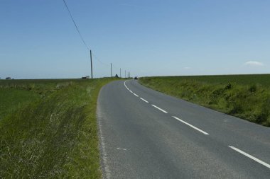 Yeşil tarım alanları üzerinden geçen ülke yol boş asfalt. Fransa'da bir güneşli bahar gününde kırsal manzara. Çevre dostu tarım, Sanayi Tarım, yol ağ konsepti
