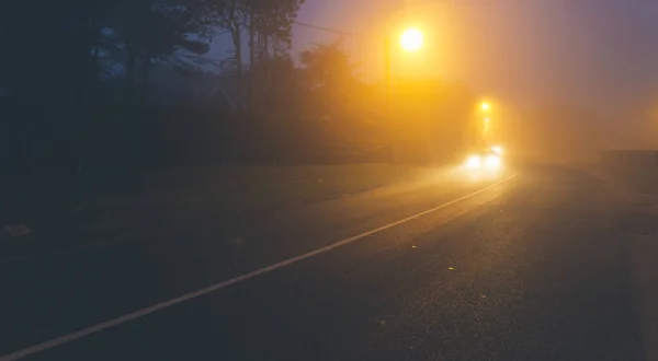 Camino de asfalto país en la región de Normandía, Francia en el día de niebla. Farolas y faros de coche por la noche. Tonificado —  Fotos de Stock