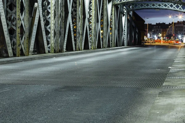 Aszfalt úton egy híd, a város acél építés alatt. Éjszaka városi táj-val autó könnyű pályák az alagútban. Tónusú — Stock Fotó