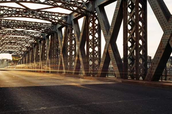 Асфальтовая дорога под стальным сооружением городского моста в солнечный день. Городская сцена в тоннеле моста. Долгое время. Toned — стоковое фото
