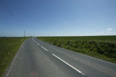 Yeşil tarım alanları üzerinden geçen ülke yol boş asfalt. Fransa'da bir güneşli bahar gününde kırsal manzara. Çevre dostu tarım, Sanayi Tarım, yol ağ konsepti