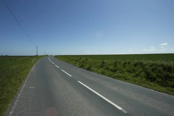 Empty asphalt country road passing through green agricultural fields. Countryside landscape on a sunny spring day in France. Environment friendly farming, industrial agriculture, road network concept — Stock Photo, Image