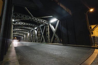 Şehirde bir köprünün çelik konstrüksiyon altında asfalt yol. Gece araba tünelde ışık yollar ile kentsel sahne. Tonda